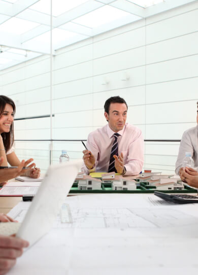 Grupo de trabajo reunido en una oficina con planos en la mesa